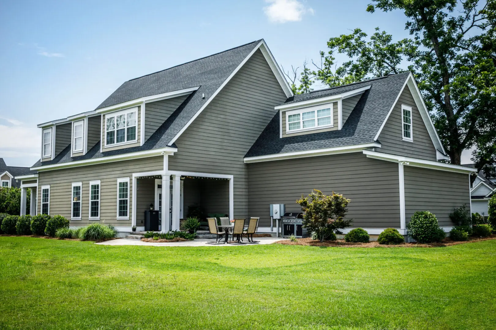 Gray suburban house with green lawn.