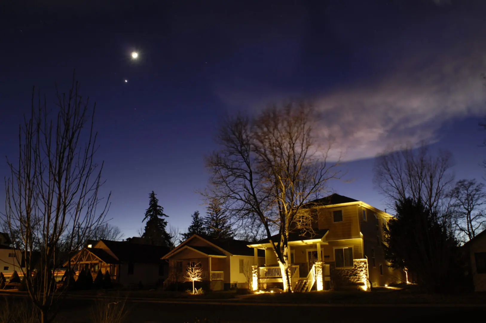 Night scene with illuminated house and trees.
