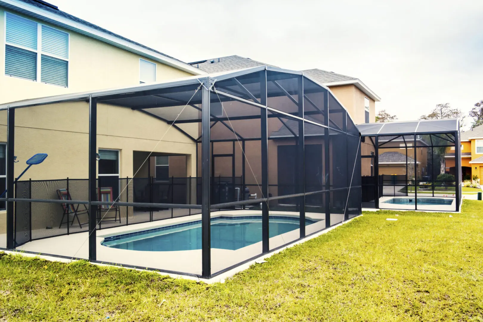 Enclosed backyard pool with mesh screen structure.