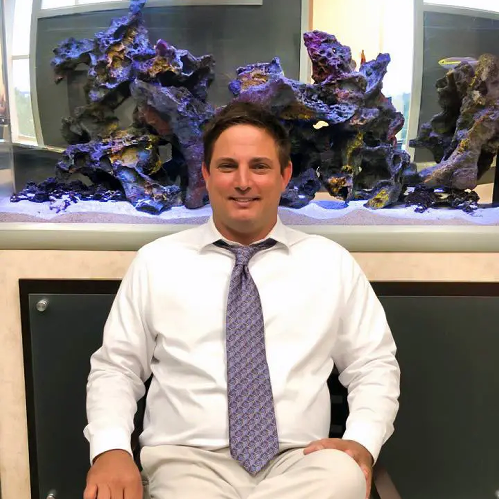 Man sitting in front of aquarium display.