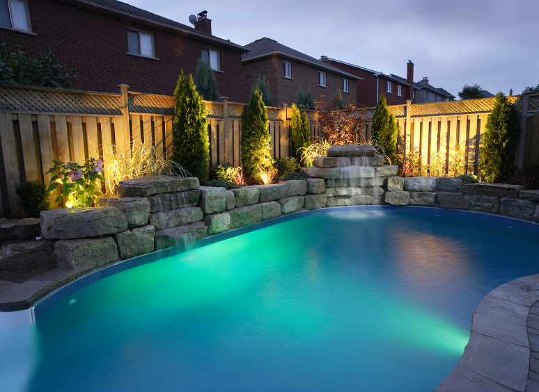 Backyard pool with evening lights and waterfall.