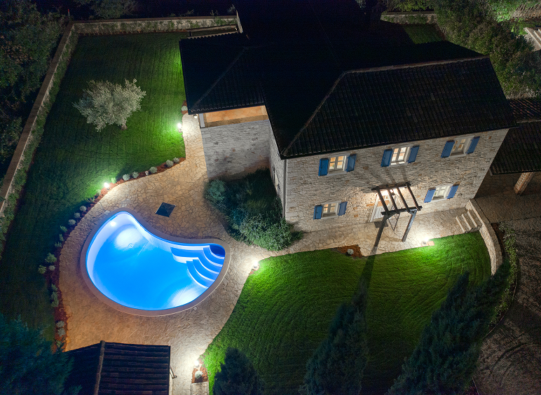 Aerial view of house with illuminated pool.