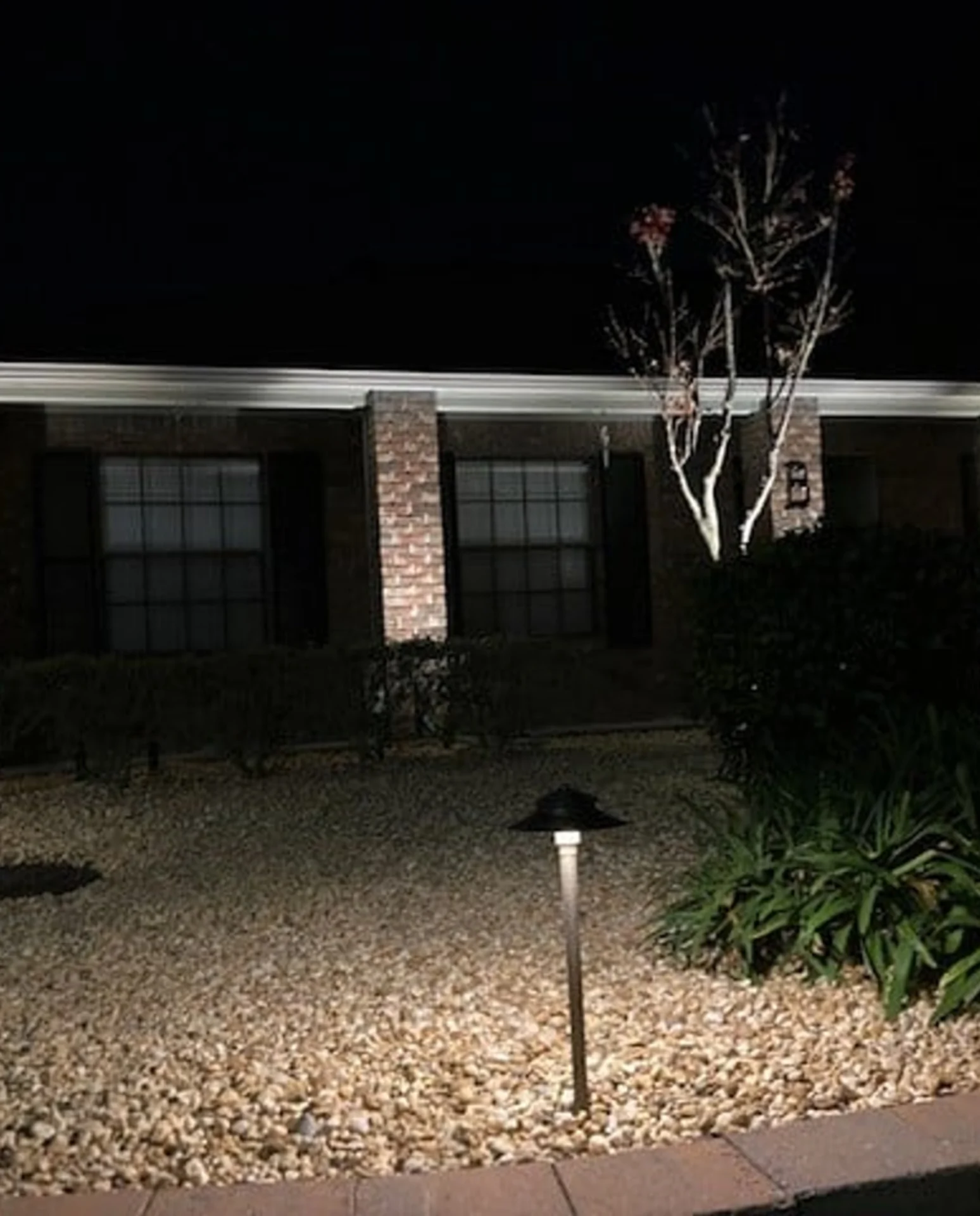 Nighttime view of house with garden lights.